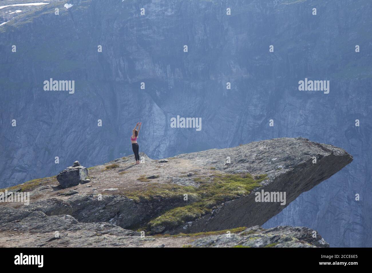 20 July 2017: Happy young woman doing exercises, doing yoga, on a mountain near the Trolltunga. The summer trip to Trolltunga hiking route. The Troll Stock Photo