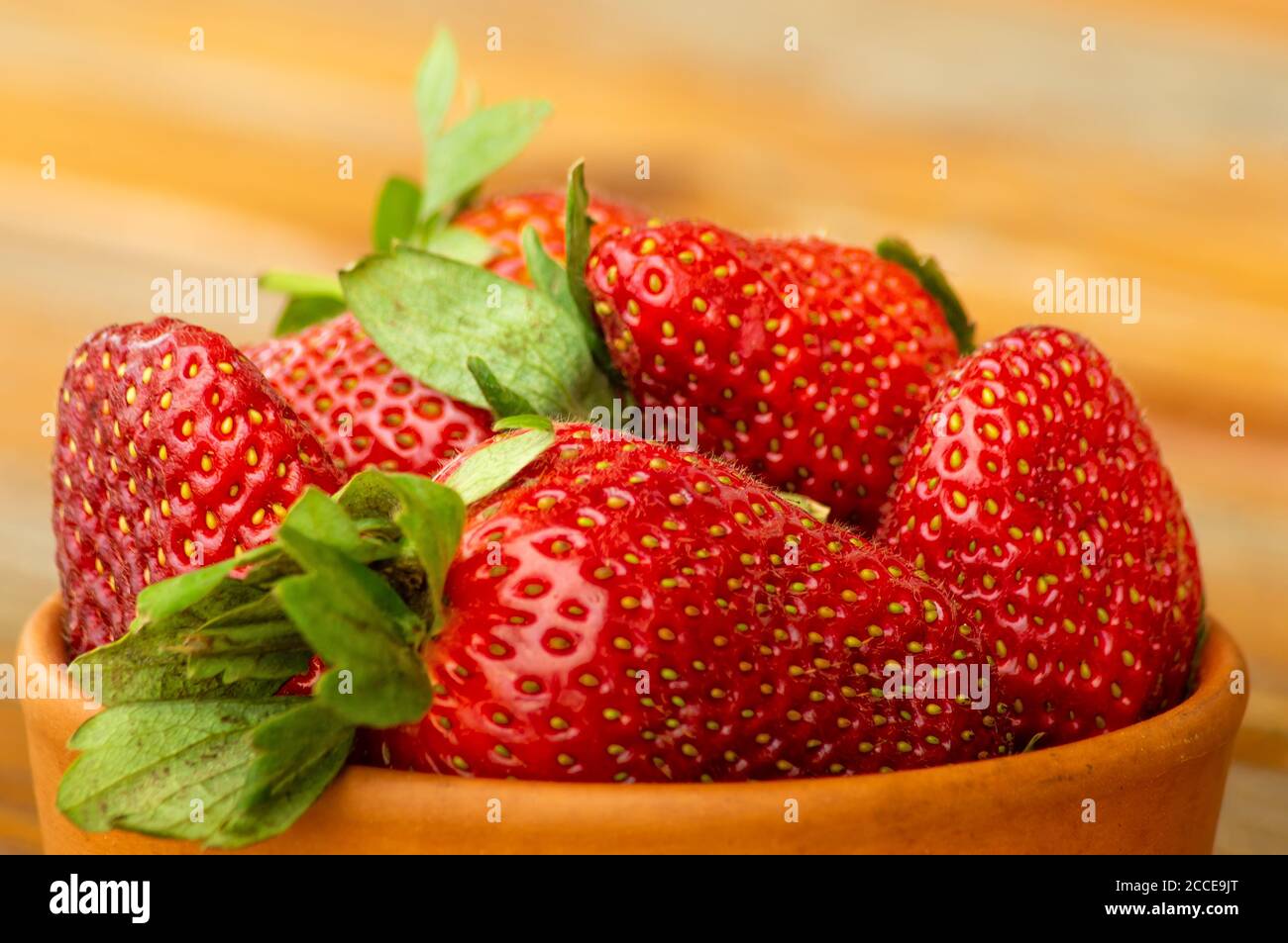 Fresh ripe red strawberries in a clay bowl on an old wooden table ...