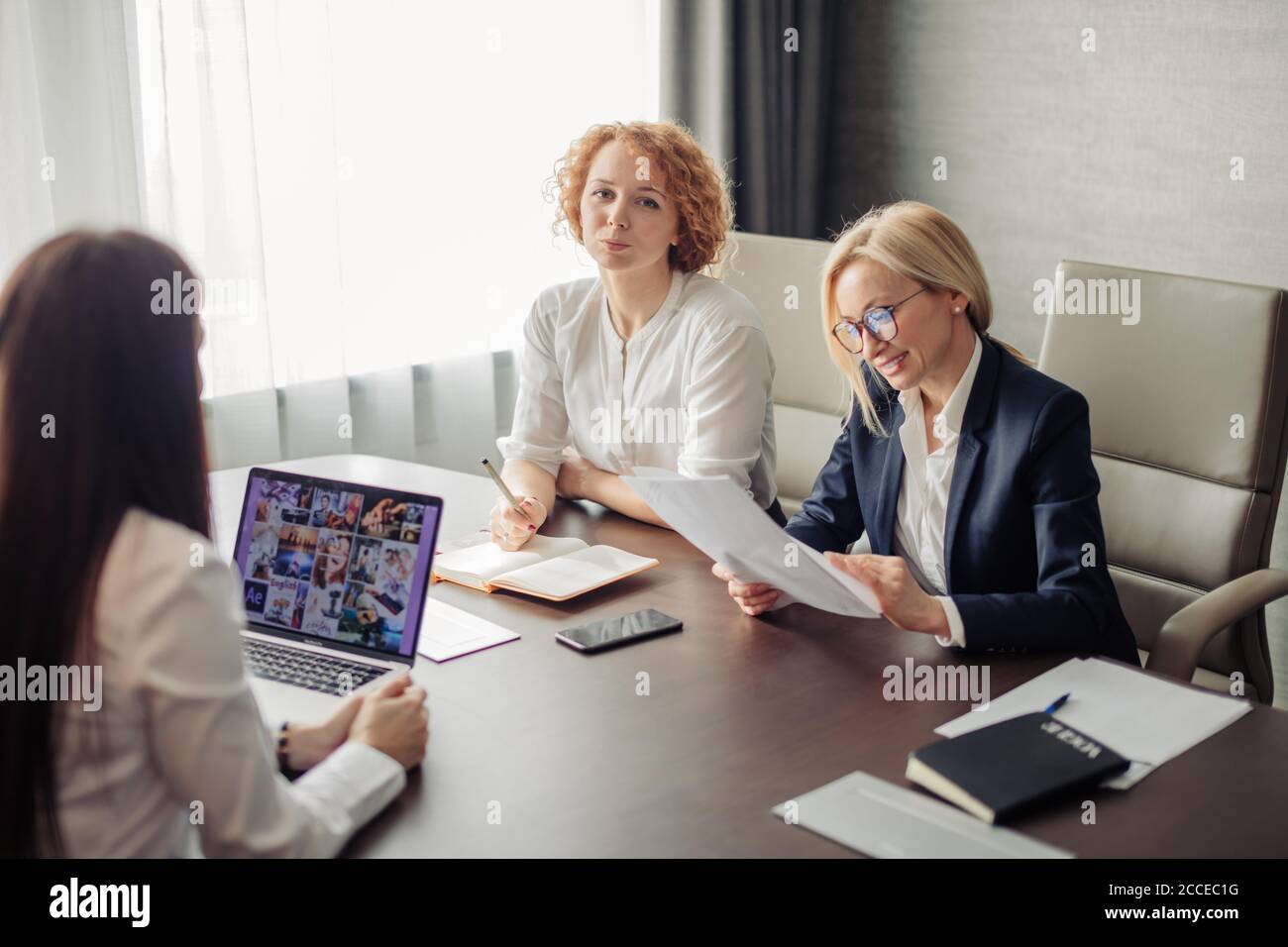 Group of two female corporate mentors check the knowledge of the woman trainee at the end of the trial period Stock Photo