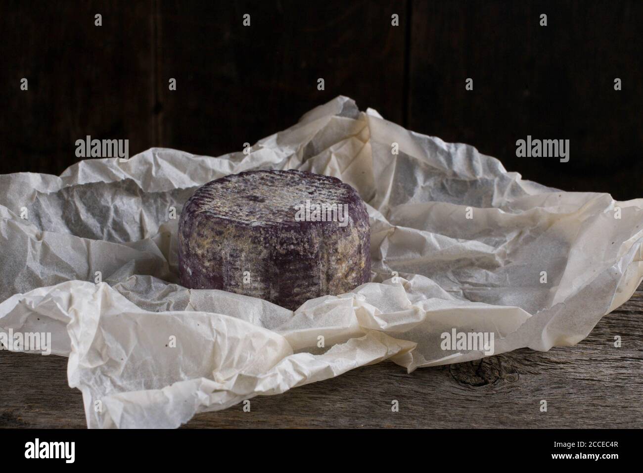 Close up of soft French cheese with purple crust on paper Stock Photo