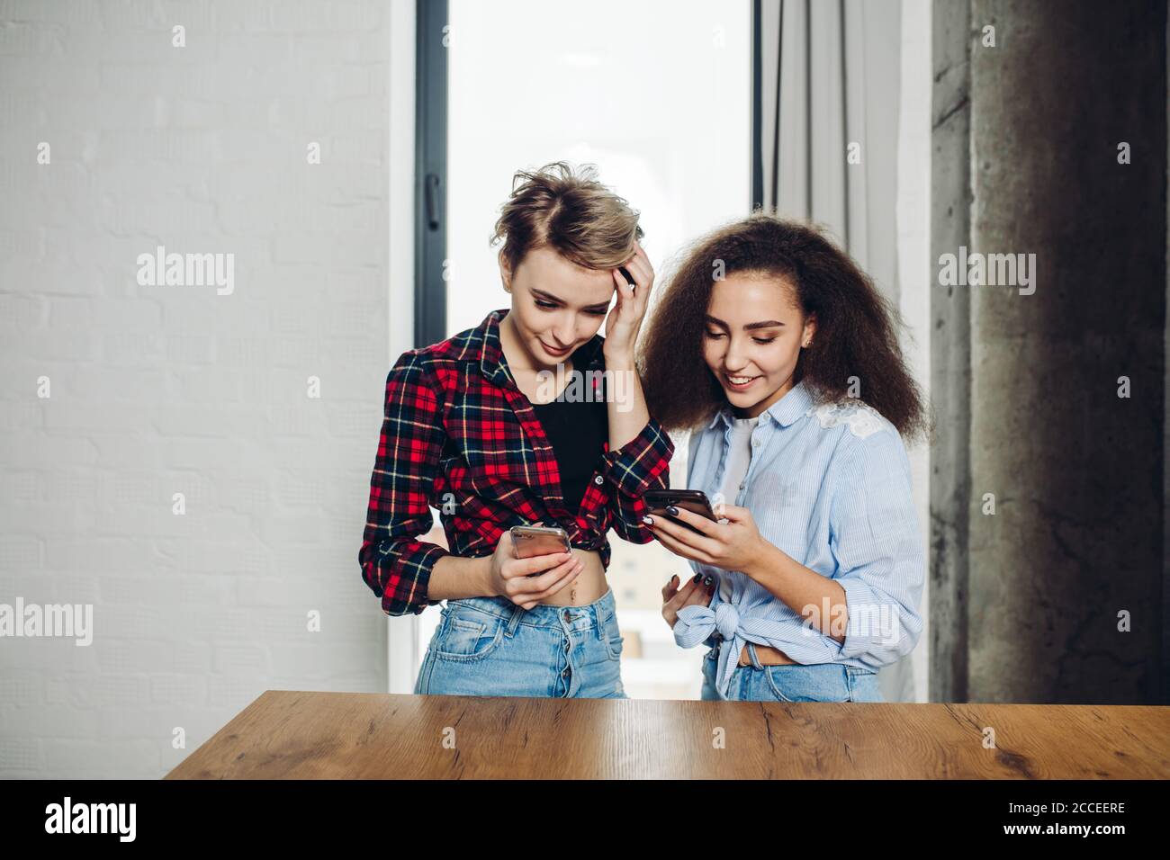 pleasant jouful women are holding smartphones and discussing something. close up photo. girl arev reading last news Stock Photo