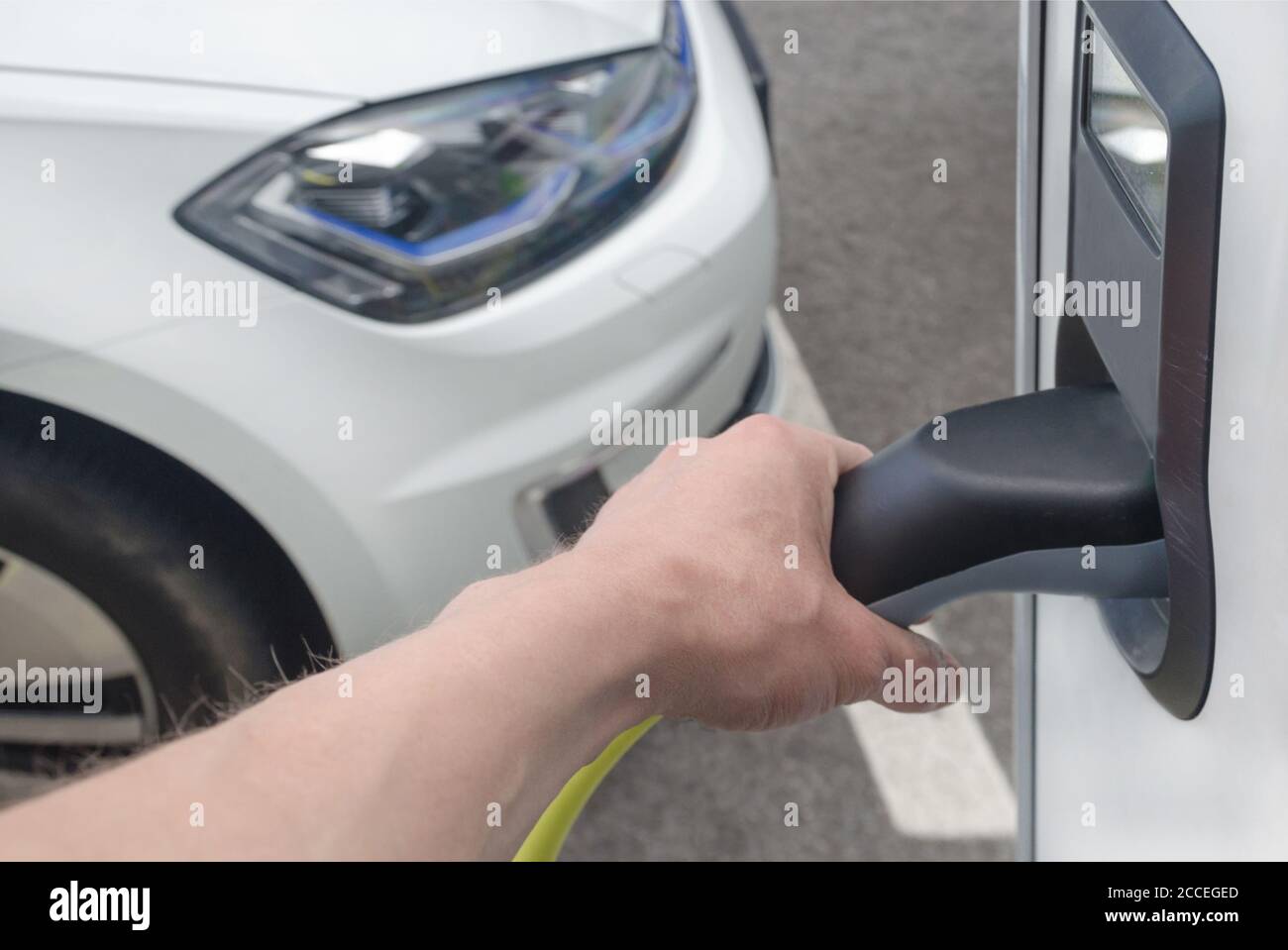 Man plugging in an electric car on the street station. New energy