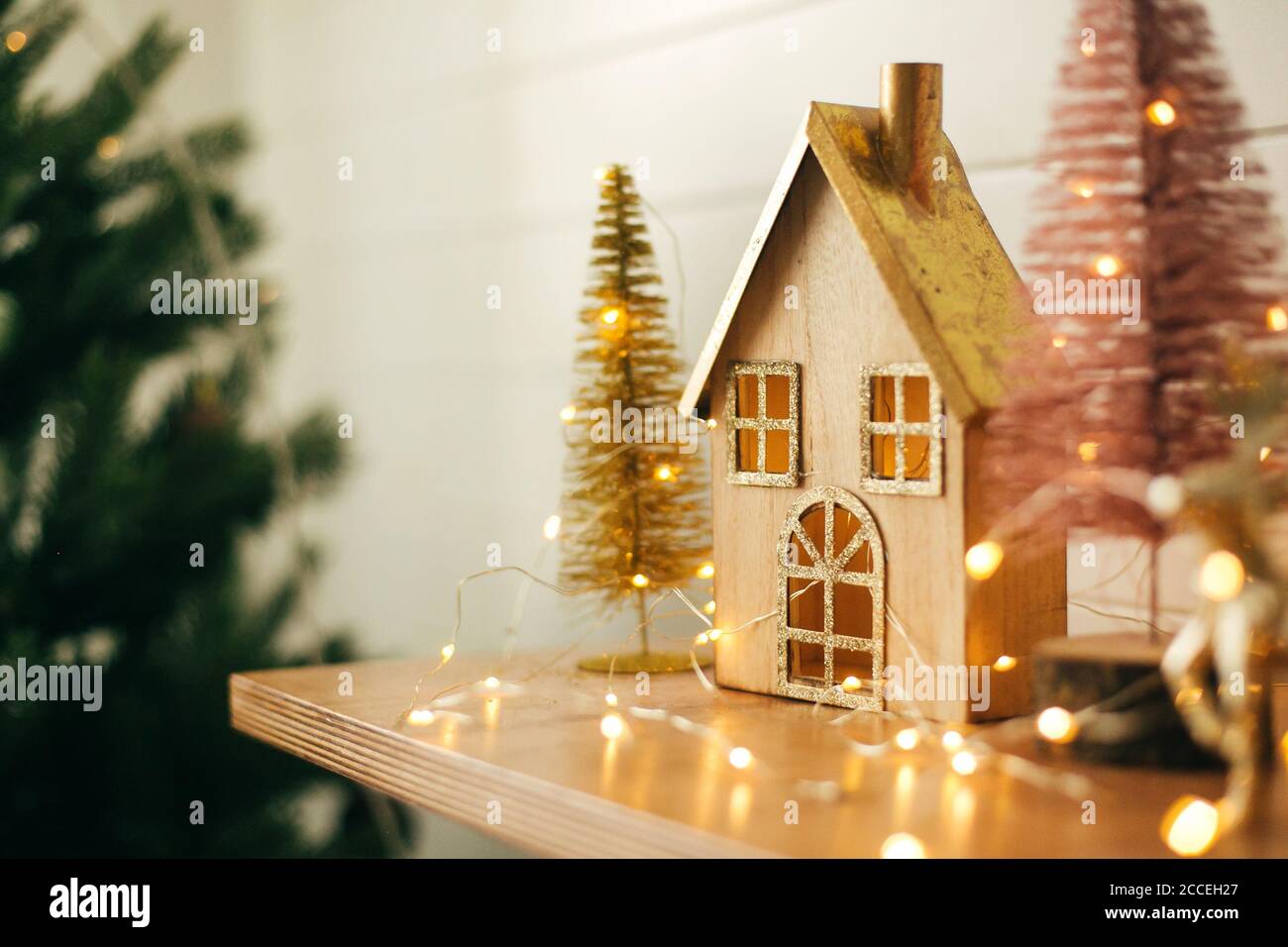 Stylish christmas wooden house, glitter christmas tree and golden ...