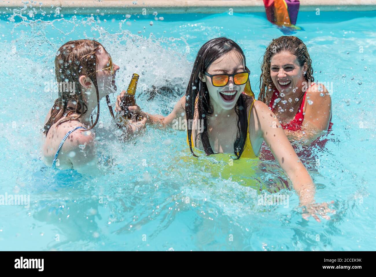 A group of young women from different ethnic groups playing splash around in a pool Stock Photo