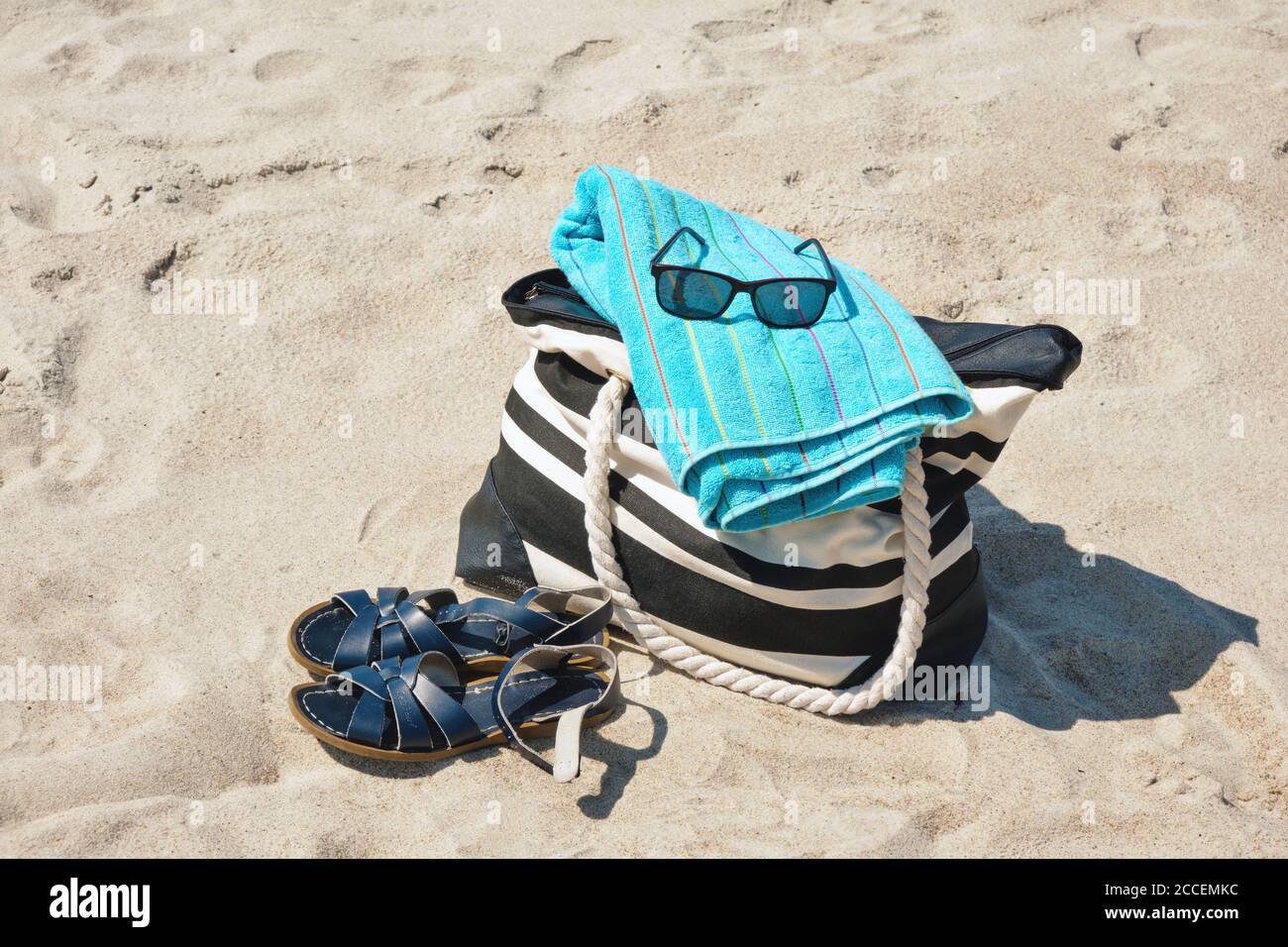 Set of personal belongings lying on the beach sand with in bright summer day Stock Photo