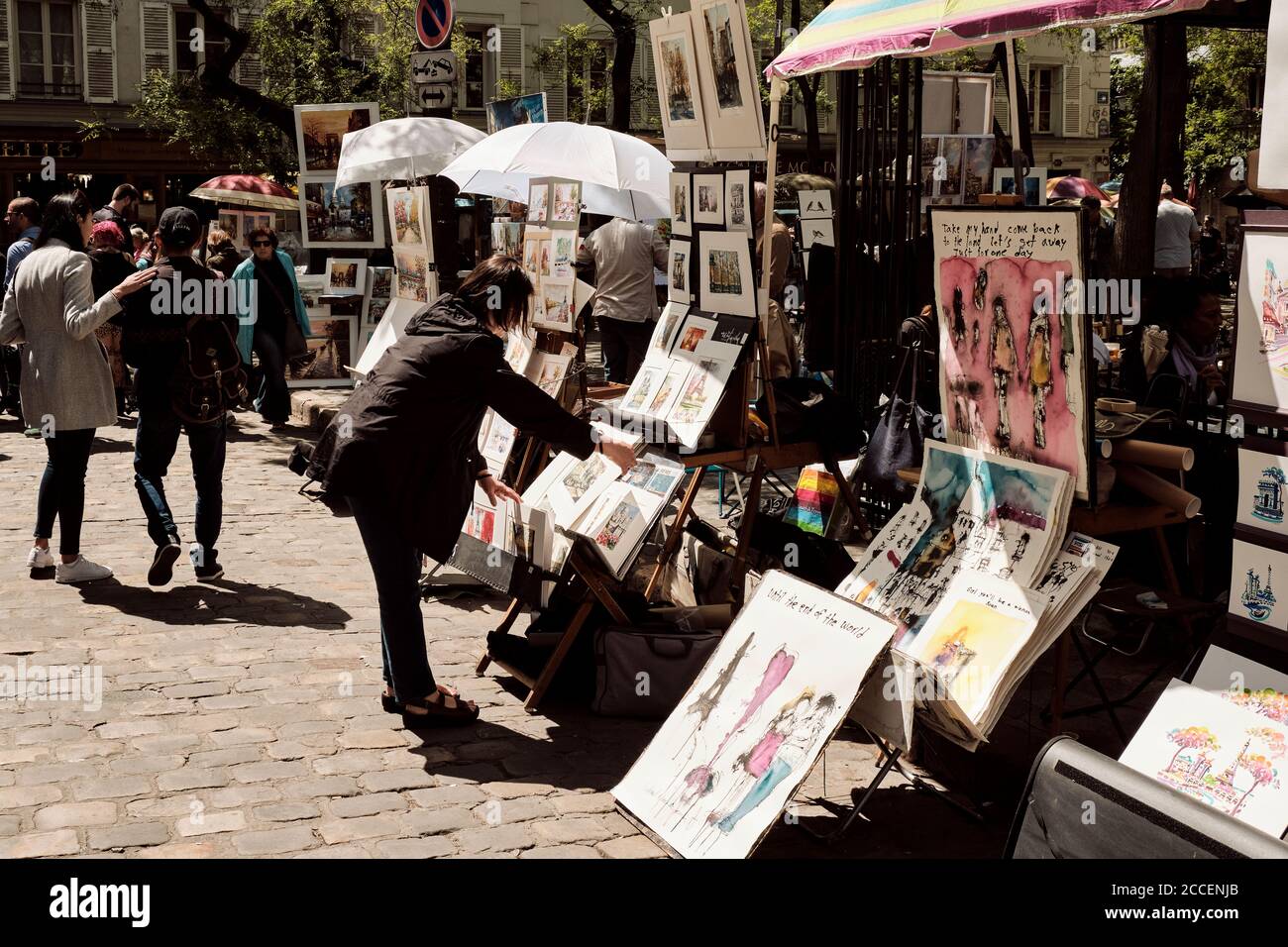 Europe, France, Paris, Montmartre, Artists painting and selling artworks on street, Woman looking at pictures Stock Photo