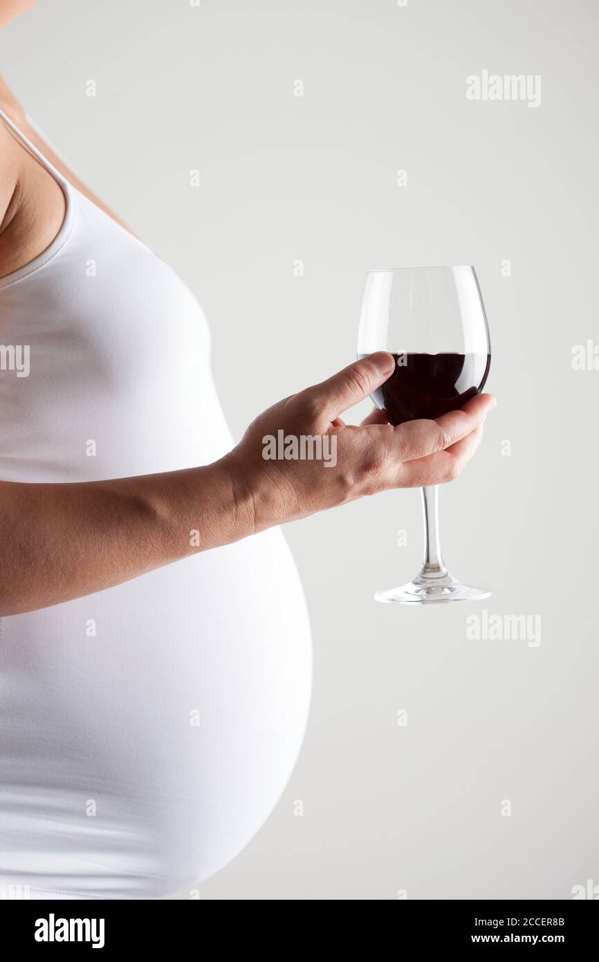 Pregnant woman holding a glass of red wine Stock Photo - Alamy