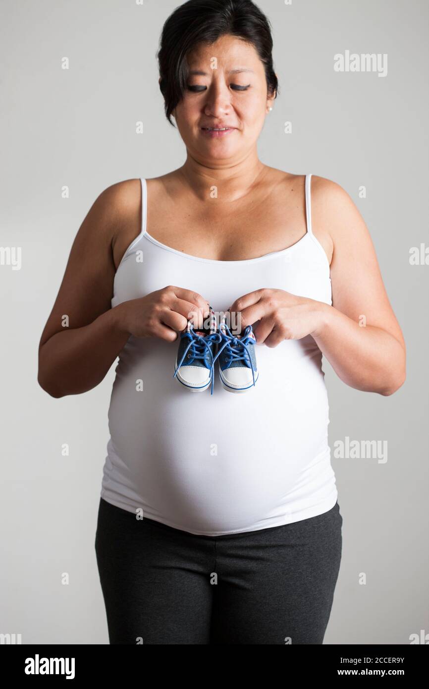 Pregnant woman holding baby shoes Stock Photo