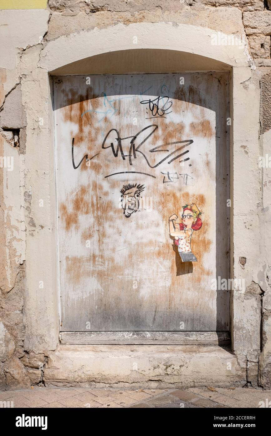Graffiti and paper sticker of a strong French woman on a weathered wooden door Stock Photo