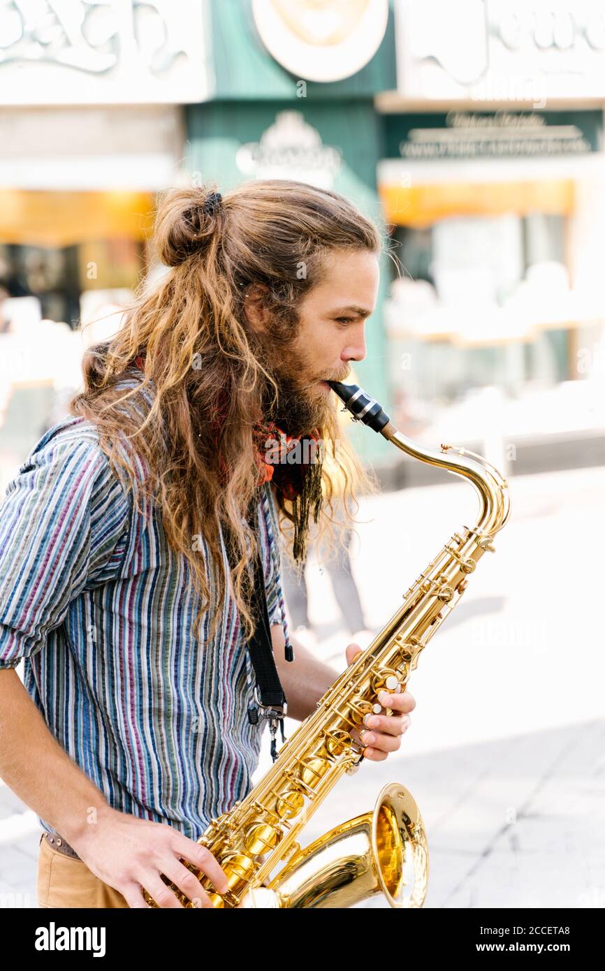 Vertical photo of the profile of a young man with long hair playing