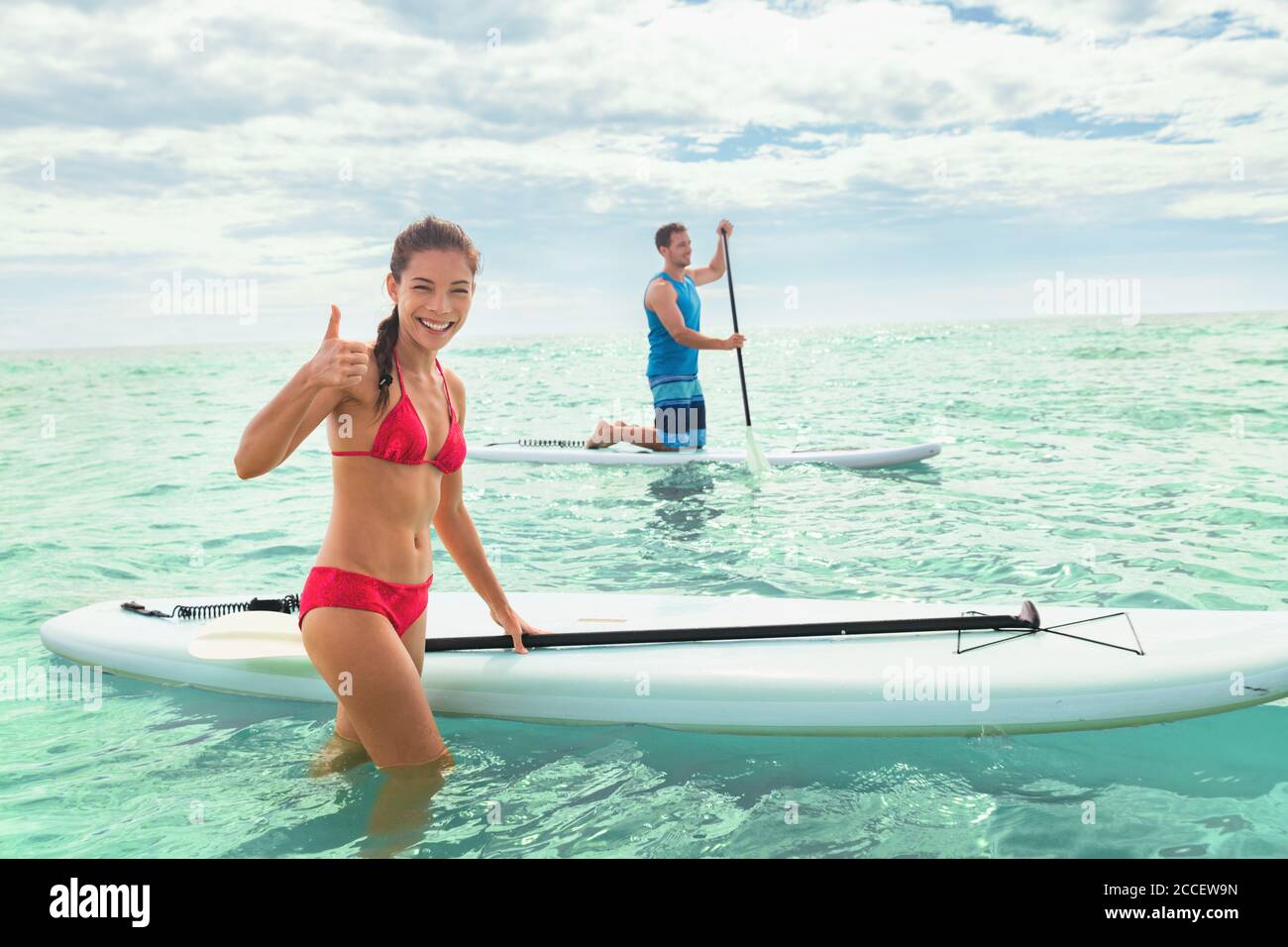 Paddleboard beach people on stand-up paddle boards surfing in ocean on Hawaii beach. Mixed race couple woman and Caucasian man enjoying watersport Stock Photo