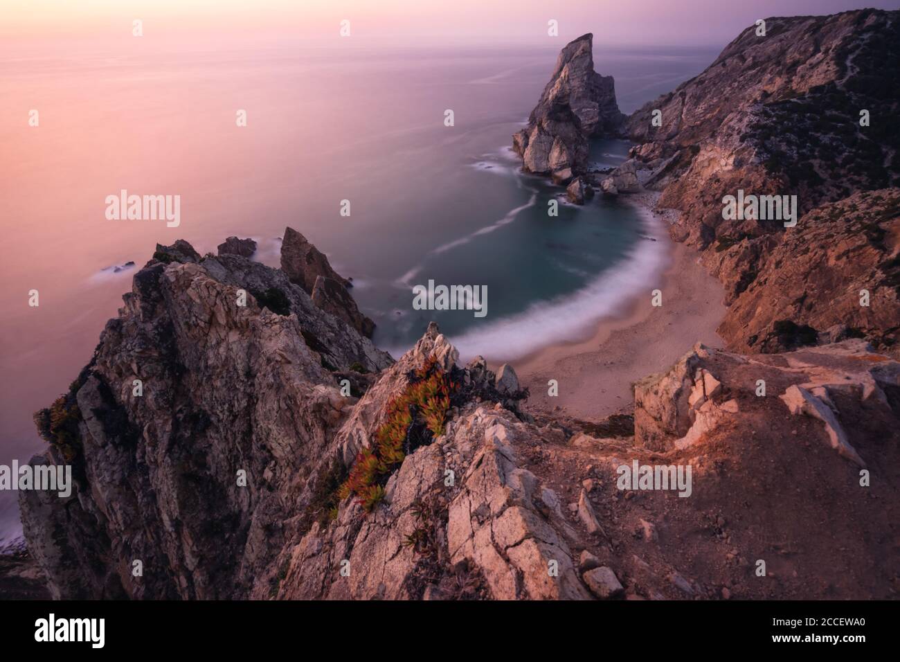 Travel to Praia da Ursa Beach, Sintra, Portugal. Landscape scene in lilac epic sunset light. Sharp cliffs and surreal coasty of Atlantic Ocean. Stock Photo