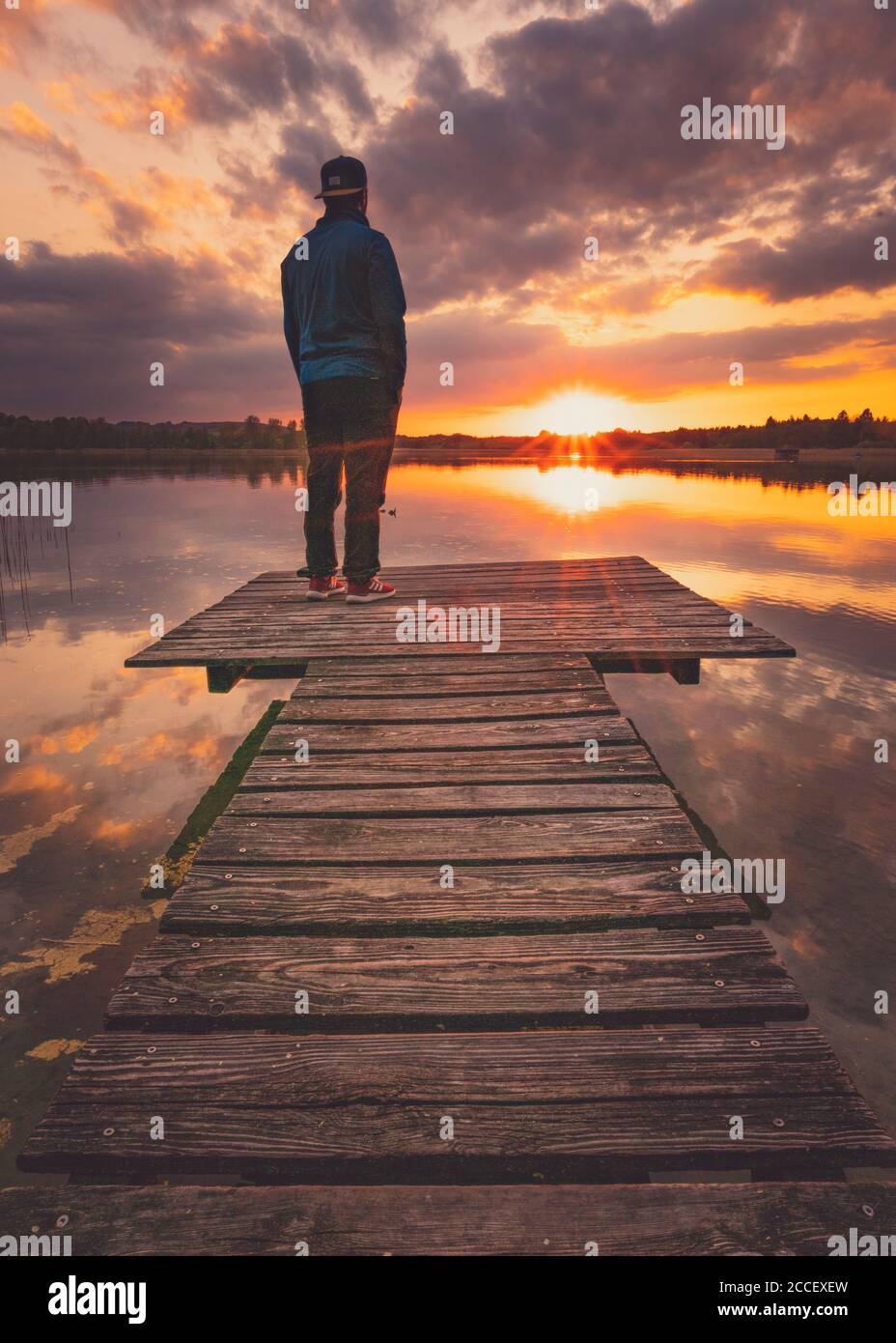 Europe, Germany, Bavaria, Breitbrunn, Chiemsee, Chiemgau, Chiemsee Lake, Man standing on jetty and looking into sunset, Stock Photo