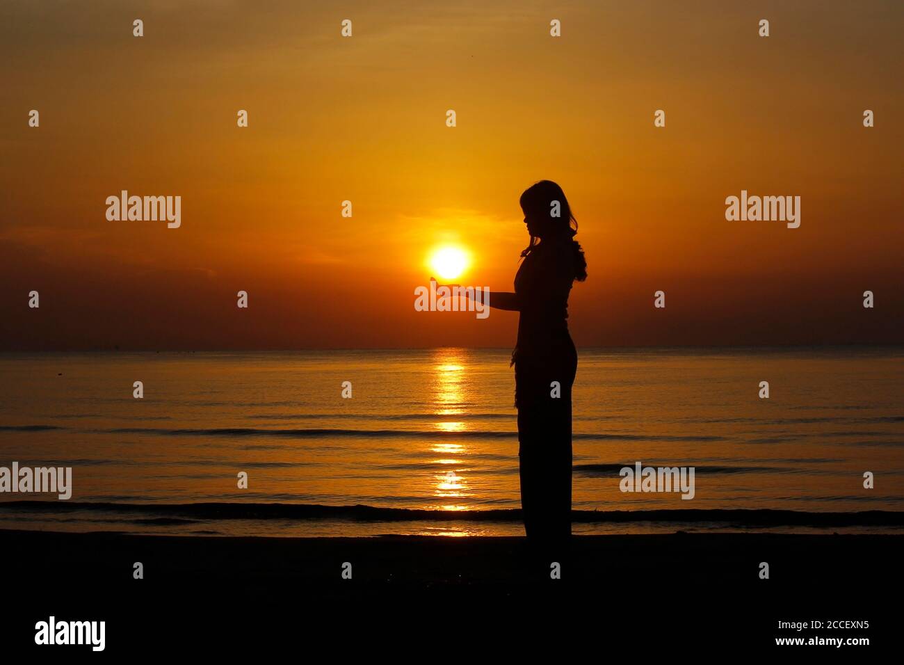 silhouette of female holding sun on the beach Stock Photo - Alamy