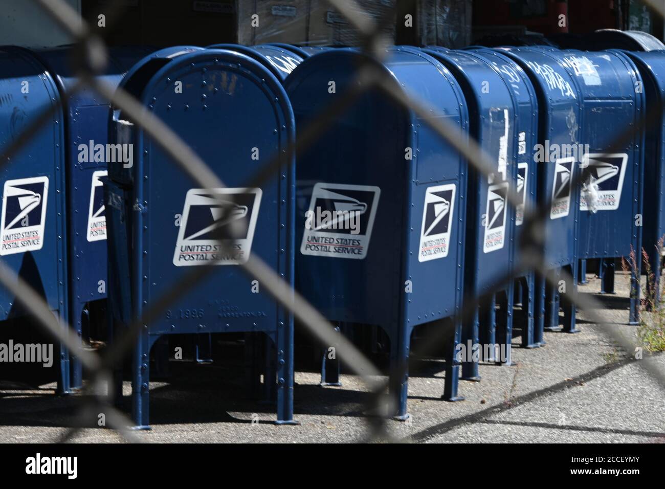 New York City, USA. 18th Aug, 2020. Seen through a perimeter fence, blue U.S. Postal Service collection boxes sit gathered in the parking lot behind a Post Office in the New York City borough of the Bronx, NY, August 18, 2020. The USPS has announced that it will stop removing mailboxes for ninety days for the expected surge of mail-in ballots rather than people going to polls due to the COVID-19 pandemic, but explained that removal was due to the lack of use. (Anthony Behar/Sipa USA) Credit: Sipa USA/Alamy Live News Stock Photo