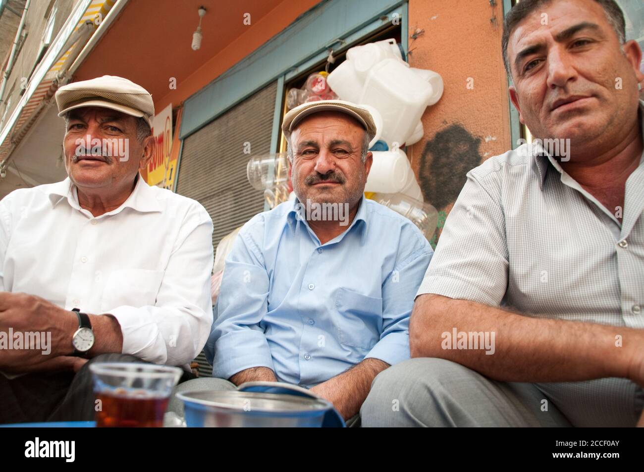 A group of three Kurdish men socialising by the roadside in the city of Van in the  eastern Anatolia region of Turkey. Stock Photo