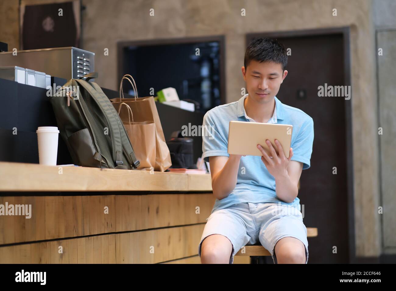 one handsome Asian young man sitting in cafe, using tablet computer. Stock Photo