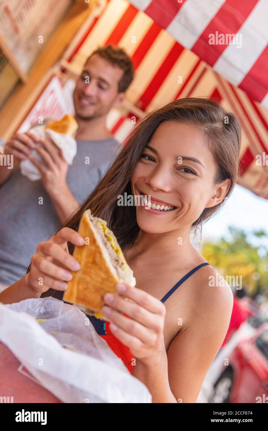 Happy Asian girl eating cuban sandwich at local cafe restaurant in Key West, Florida. Summer travel tourist lifestyle young Asian woman smiling eating Stock Photo