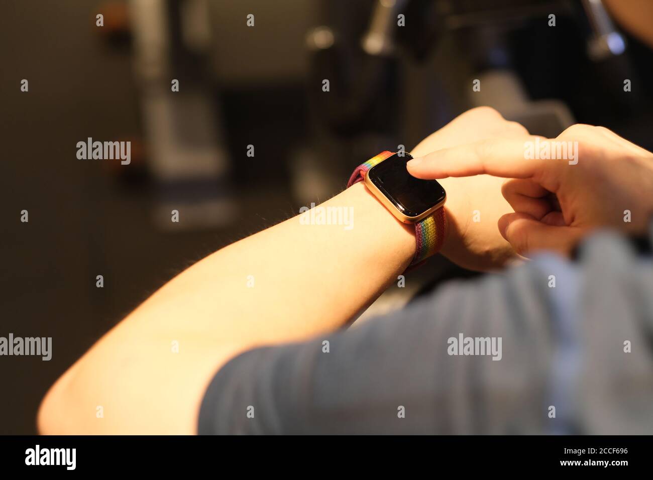 over shoulder of man touching smart watch in gym. blur background Stock Photo