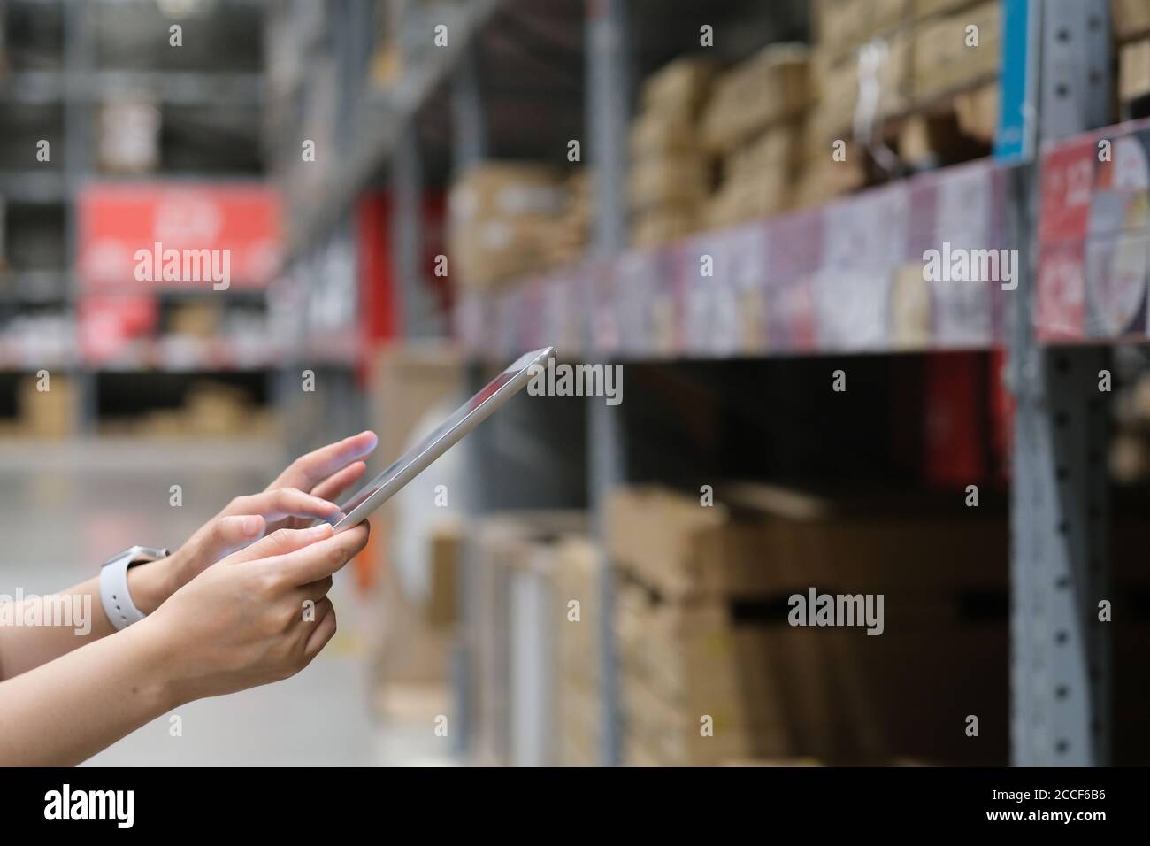 close up hands using tablet with blurred goods shelf background. warehouse, store concept Stock Photo