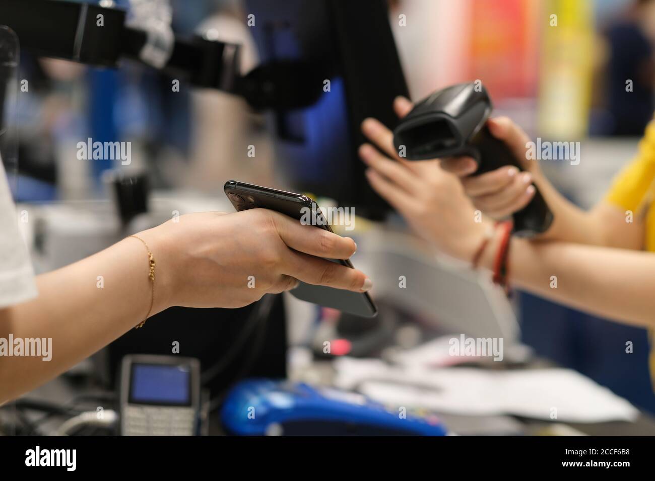 close up hand holding phone to scan to pay at checkout. contactless payment. soft focus Stock Photo