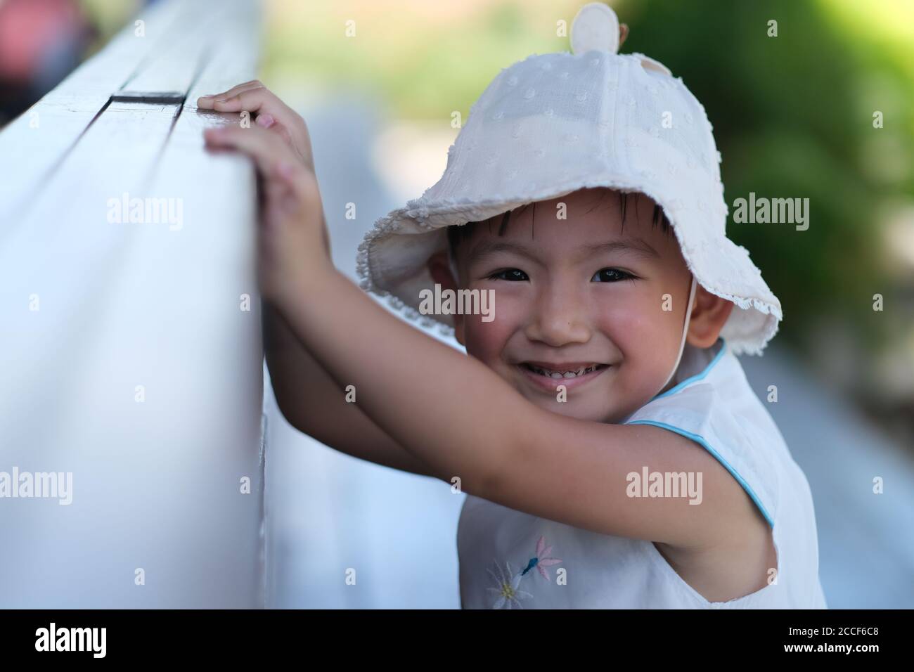 close up one Asian toddler in white hat, smiling and looking at camera Stock Photo