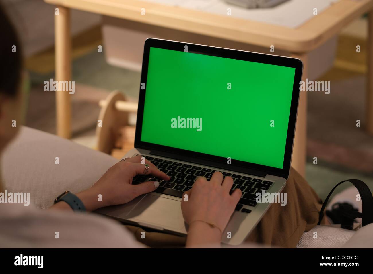 over shoulder view of people using green screen laptop computer at home. working at home concept. blur background Stock Photo