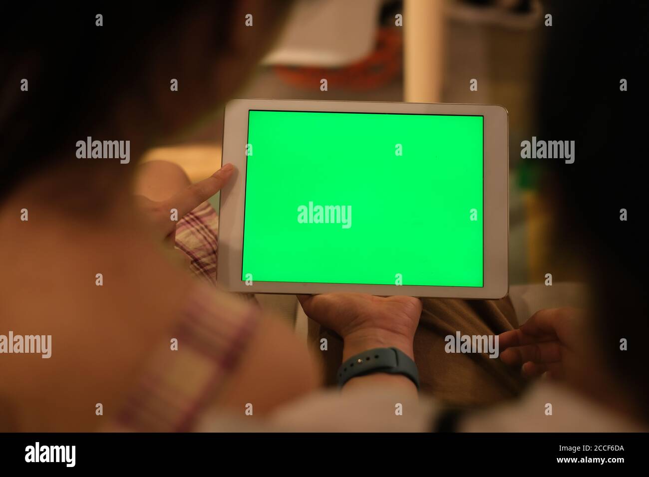 over shoulder view of two women looking at green screen tablet together at home Stock Photo