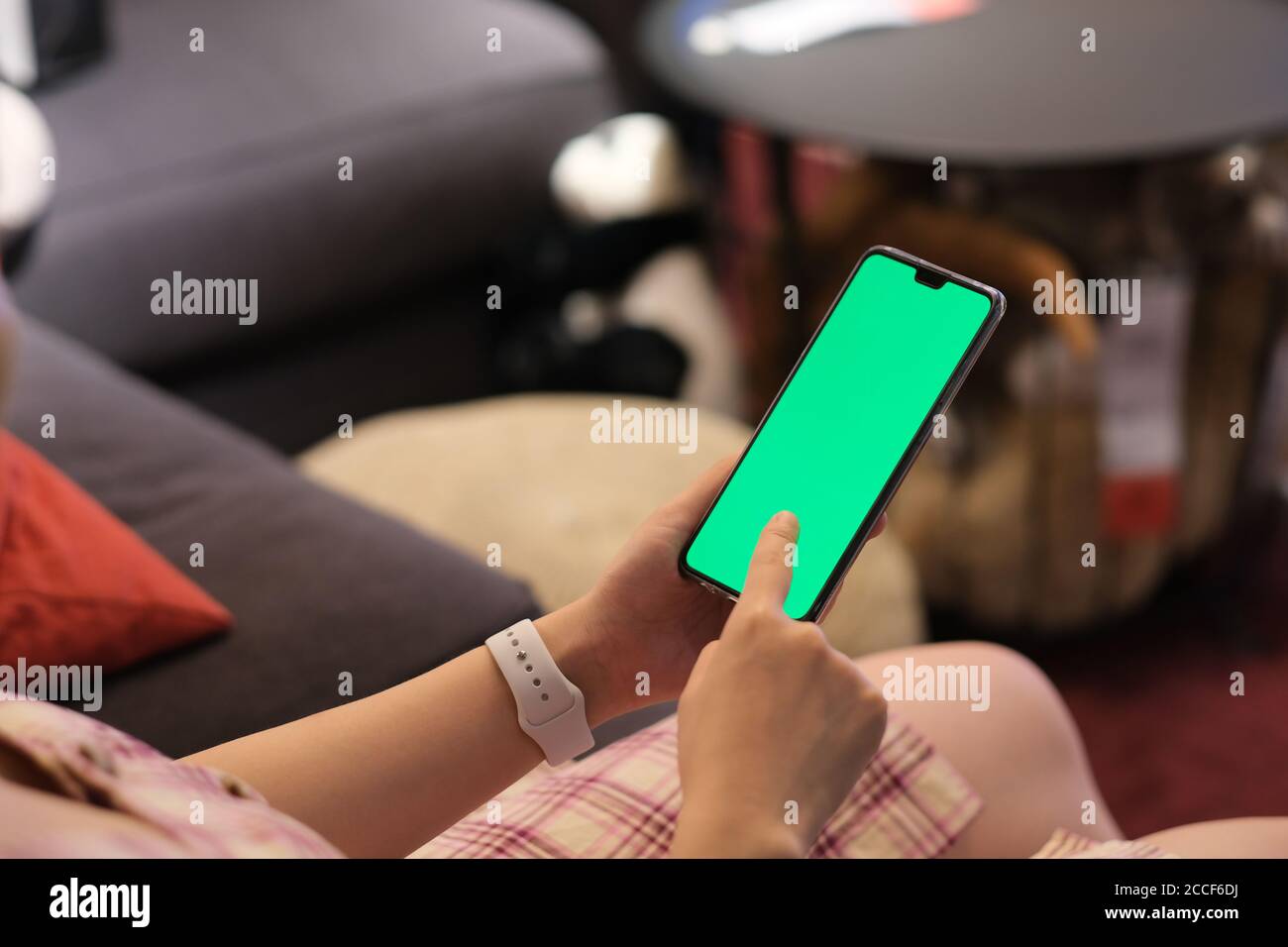 over shoulder view of people touching green screen phone at home. blur background Stock Photo