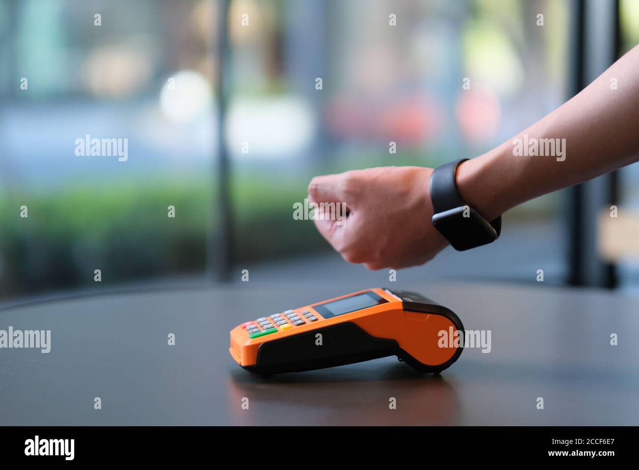 close up people using smart watch to pay over pos terminal on table. blur background Stock Photo