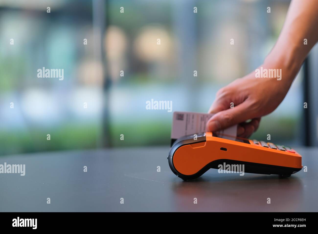 close up hands swiping the credit card on pos terminal. colorful bokeh background Stock Photo