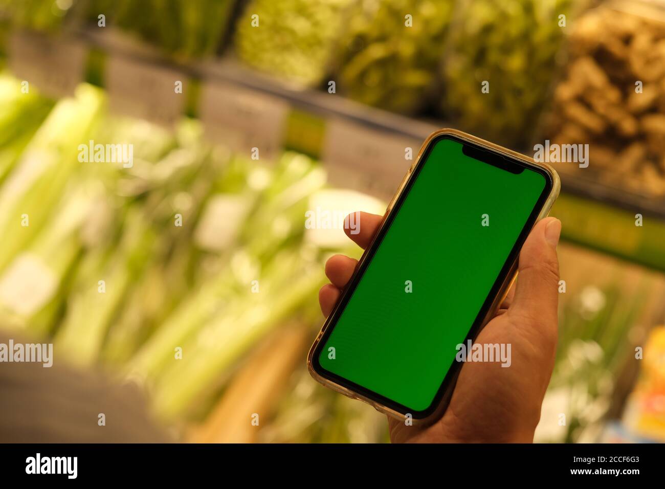 over shoulder of people holding green screen smart phone at grocery store Stock Photo