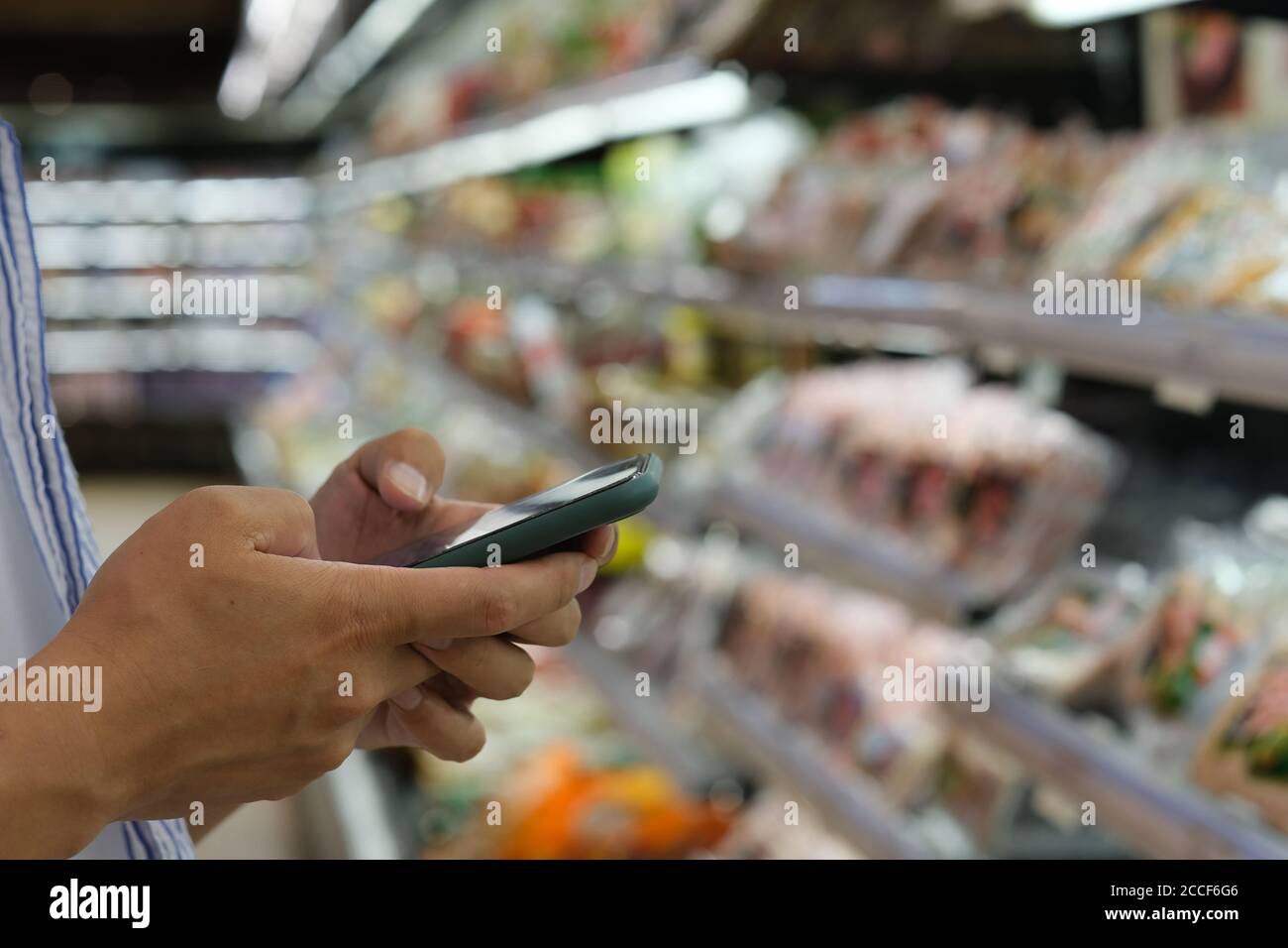close up hands using smart phone at grocery store Stock Photo