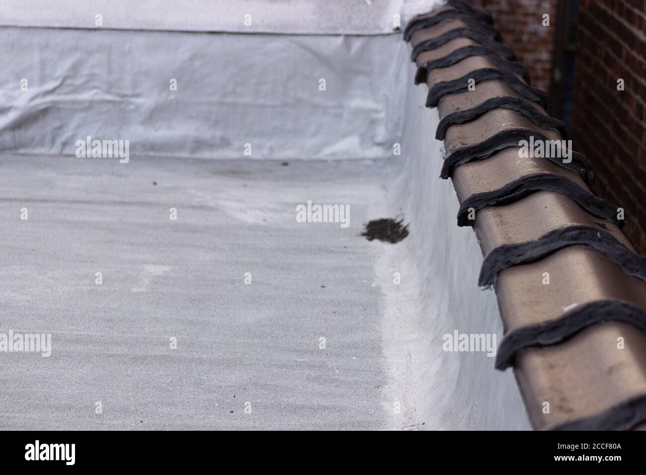 Painted terra cotta tiles, gaps filled with caulk and tar, on a 1920s era rooftop in the Bronx. Stock Photo