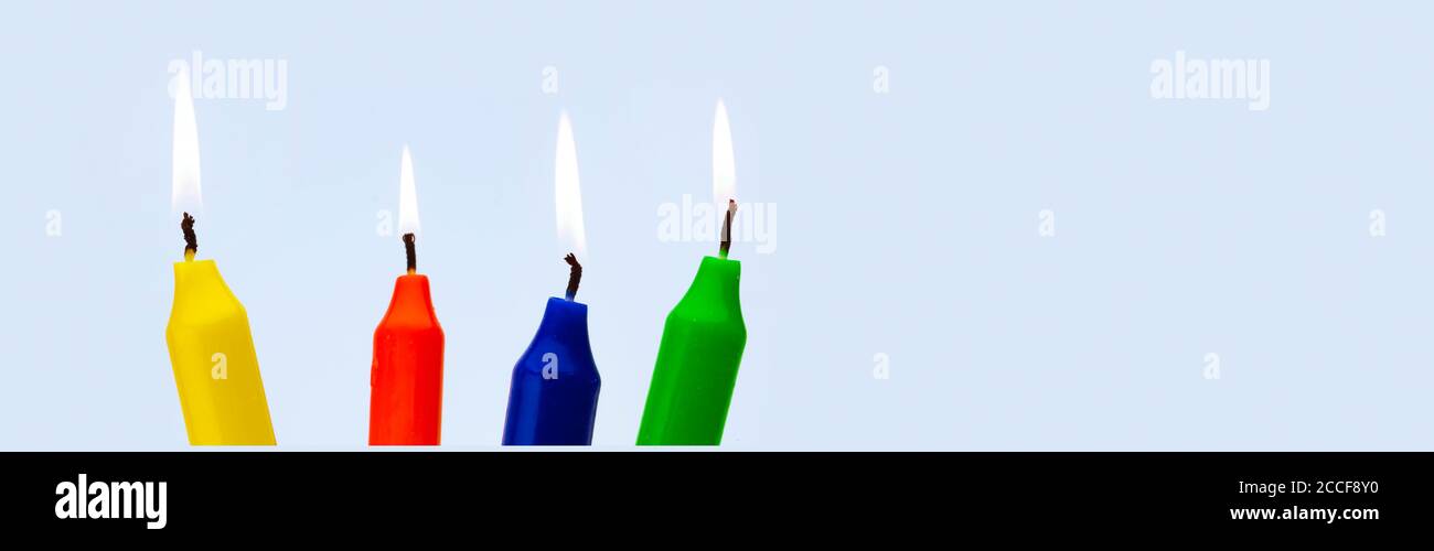 Colorful burning candles against a light blue background Stock Photo