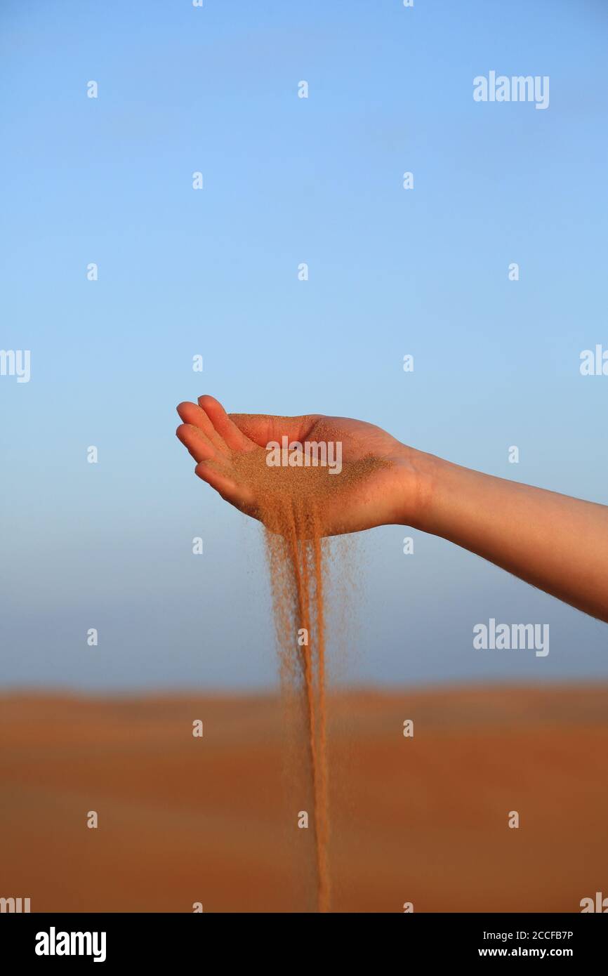 Sand falls from a woman's hand Stock Photo