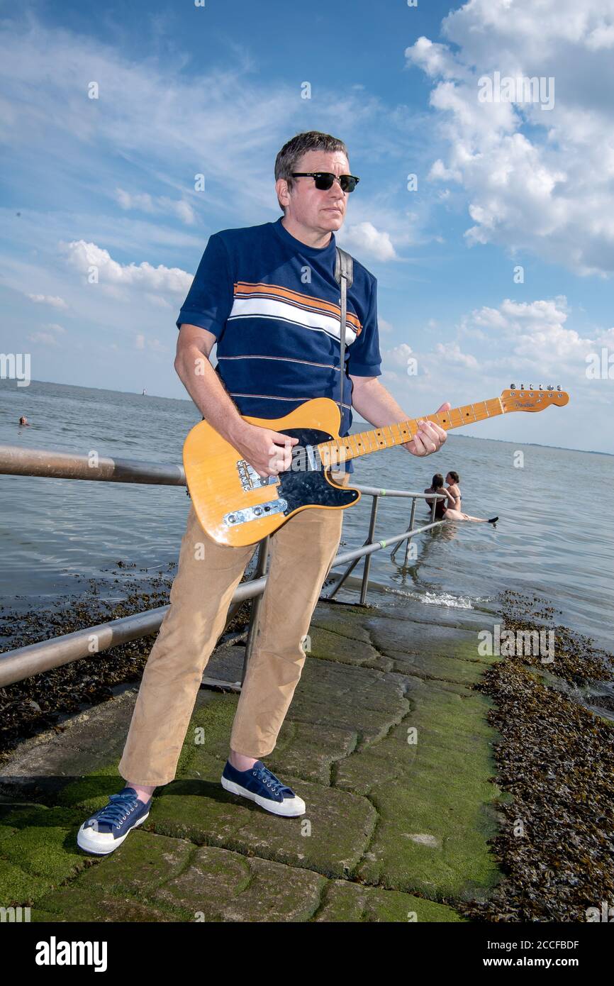Wilhelmshaven, Germany. 19th Aug, 2020. Ralf Lübke, musician, is standing on the south beach with his guitar. A song against loneliness and existential fears - 40 Wilhelmshaven musicians produced a video as a sign of life during the Corona crisis. Credit: Sina Schuldt/dpa/Alamy Live News Stock Photo