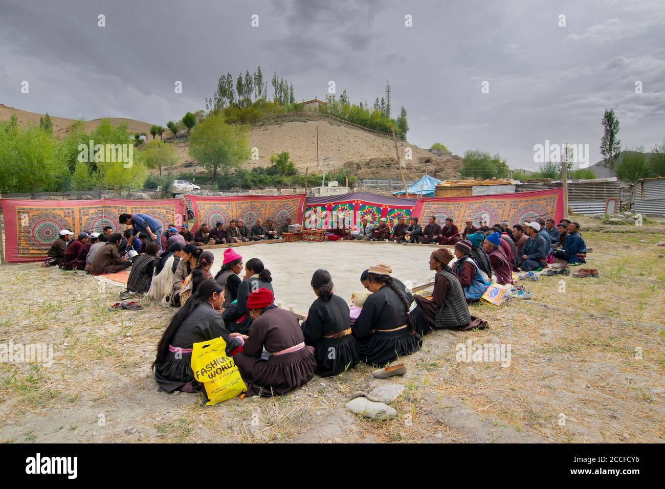 Mulbekh, Ladakh, India - 2nd September 2014 : Ladakhi people in traditional dresses, gathered for religious festival. Himalayan mountains backdrop. Stock Photo