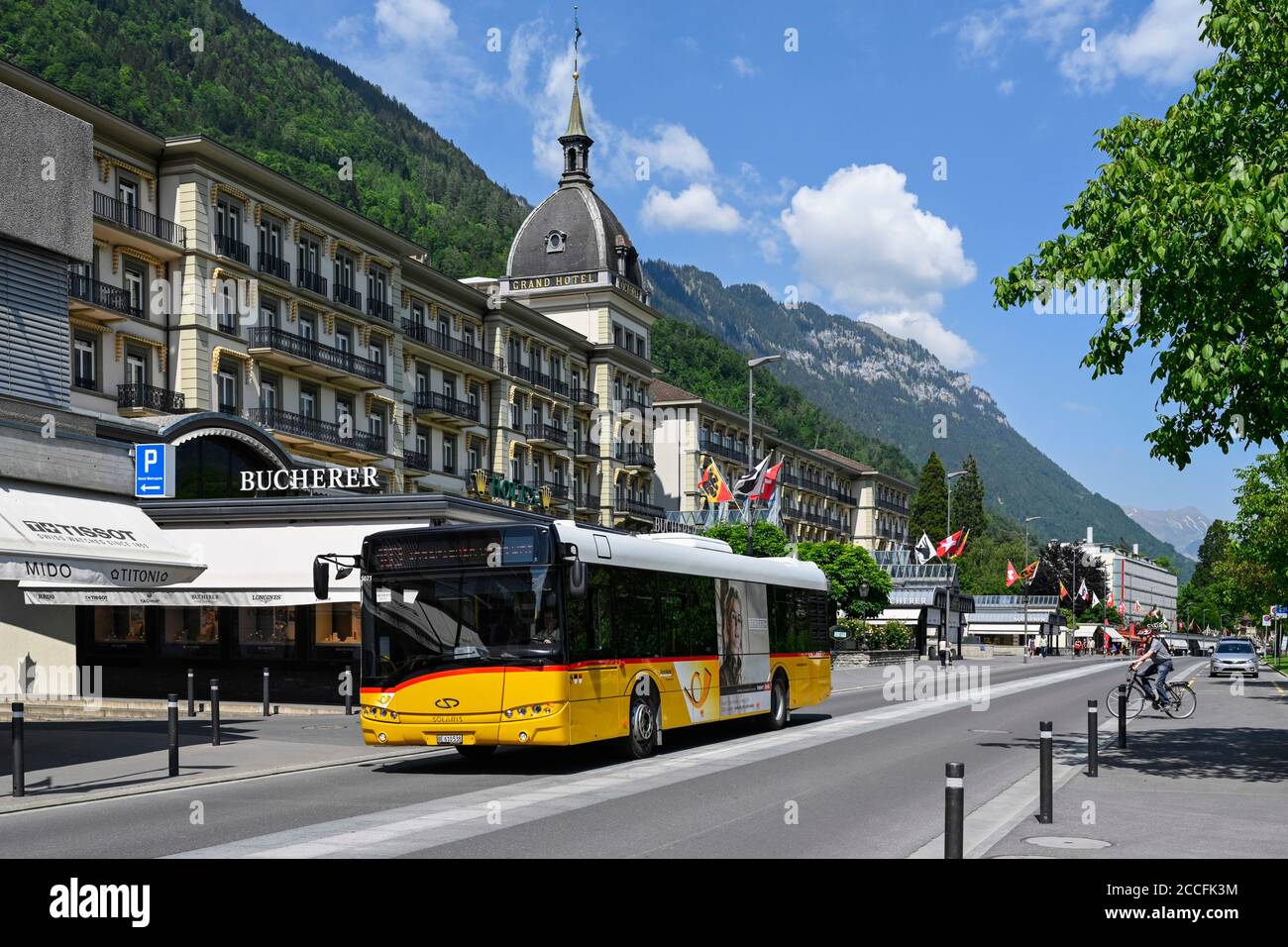 Postbus with the Victoria Jungfrau Grand Hotel in the background, Interlaken, Switzerland Stock Photo