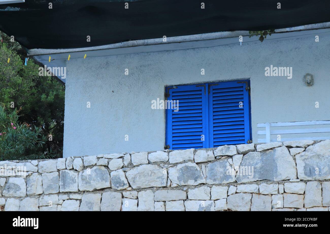 Part of a typical Mediterranean house with a stone wall and blue ...