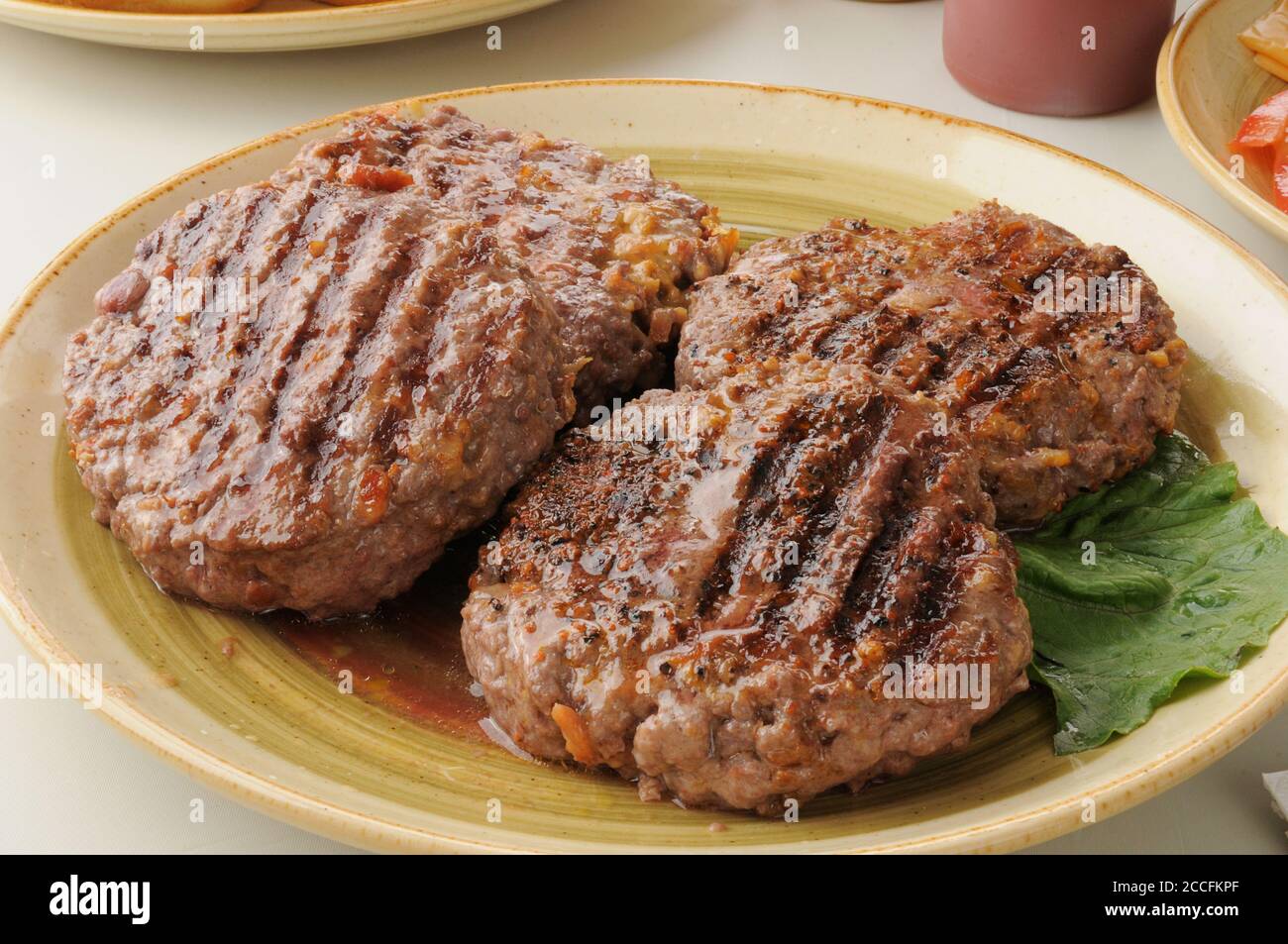 A serving platter of thick juicy grilled hamburger patties stuffed with