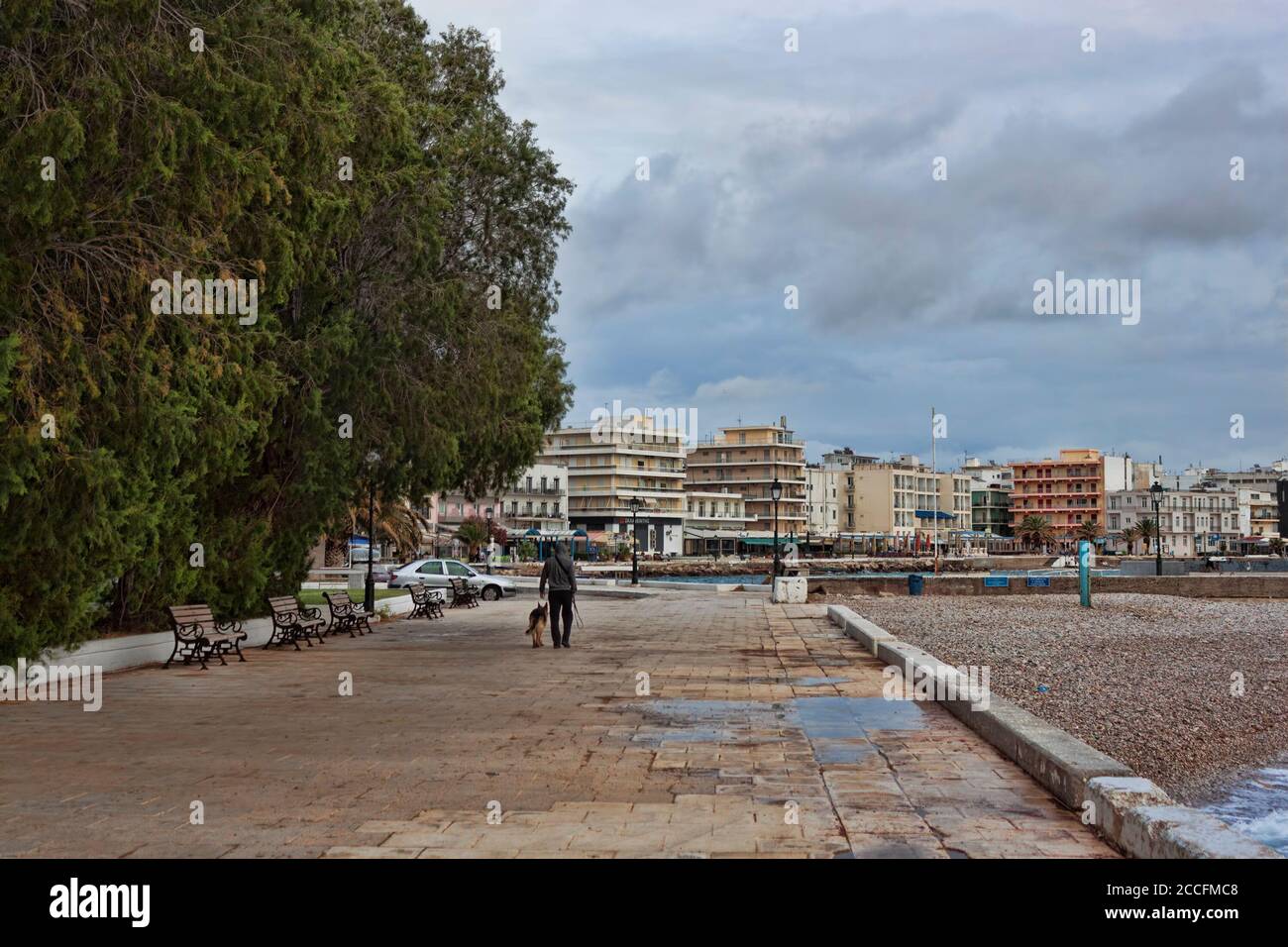 LOUTRAKI, GREECE - JUNE 27, 2020: On a cloudy day on the deserted promenade of Loutraki, only one man with a dog Stock Photo