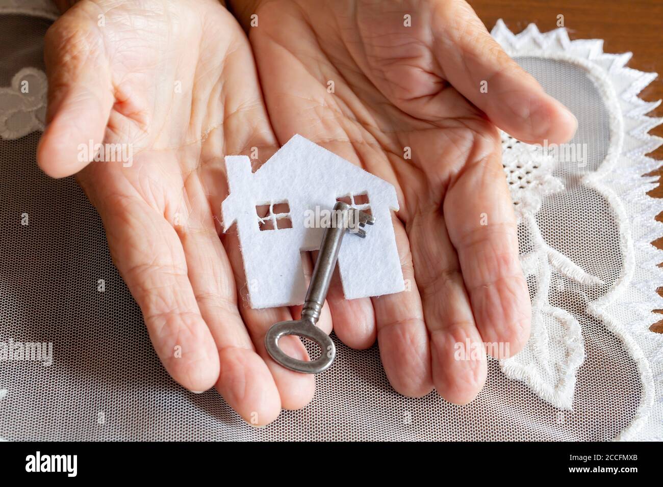 Old woman holding  house model and house key in hand.Mortgage loan approval home loan and insurance concept Stock Photo