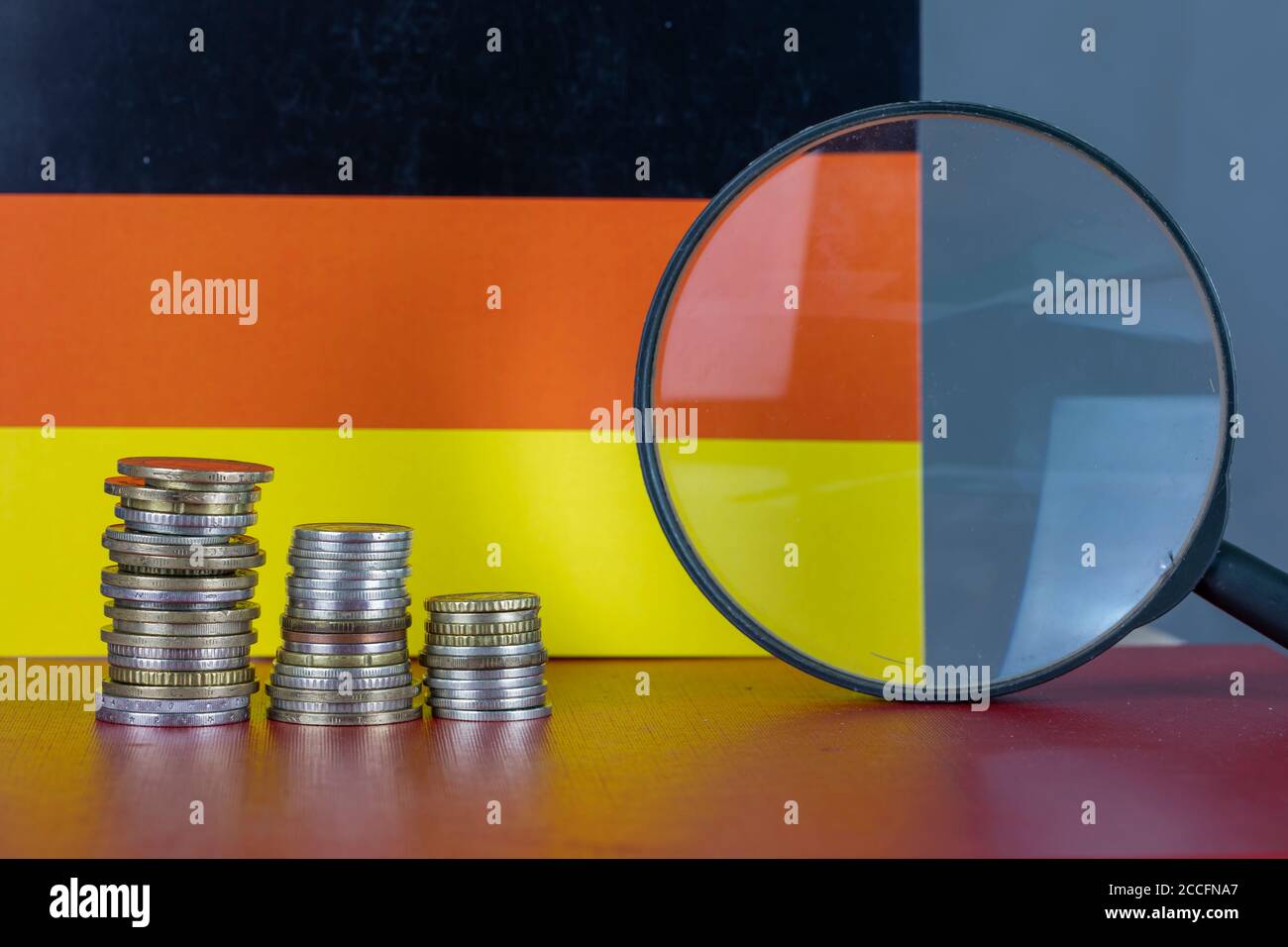 Magnifying glass and coins in front of Germany flag, country economy concept Stock Photo