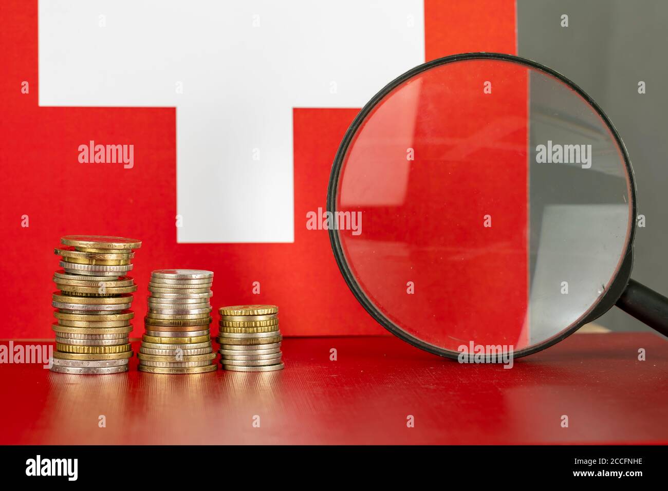 Magnifying glass and coins in front of Switzerland flag, country economy  concept Stock Photo - Alamy