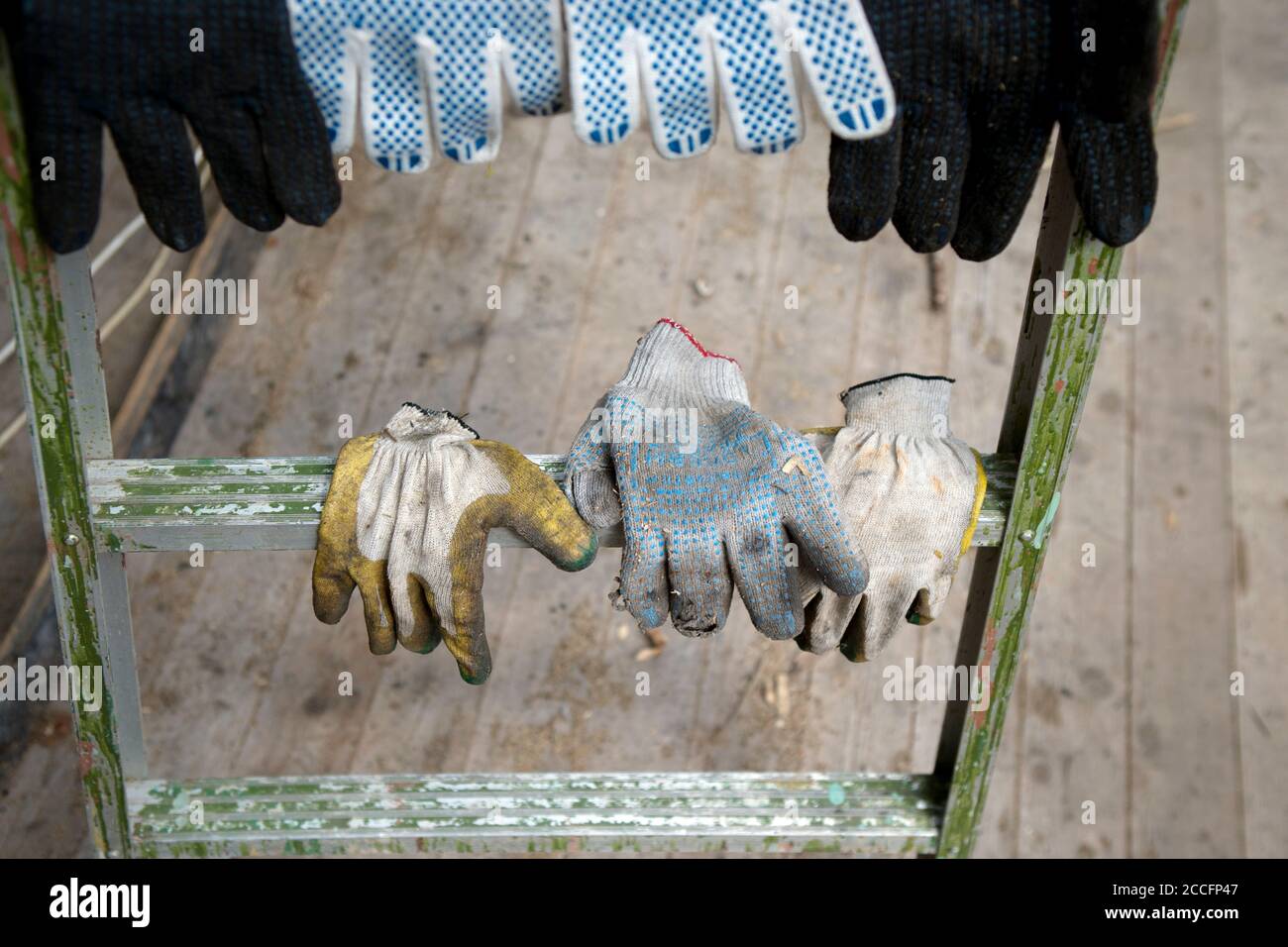Worker textile used gloves hanging on a ladder, outdoor shot Stock Photo