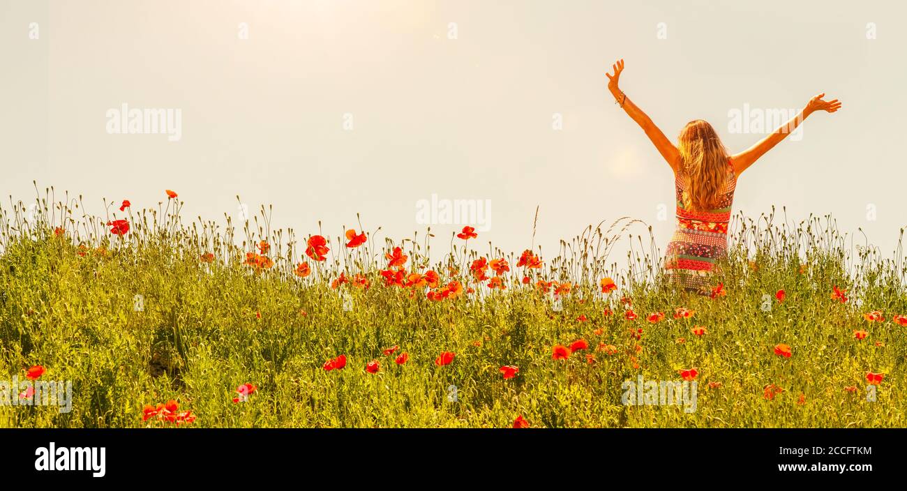 Happy woman wearing summer dress in poppy field Stock Photo