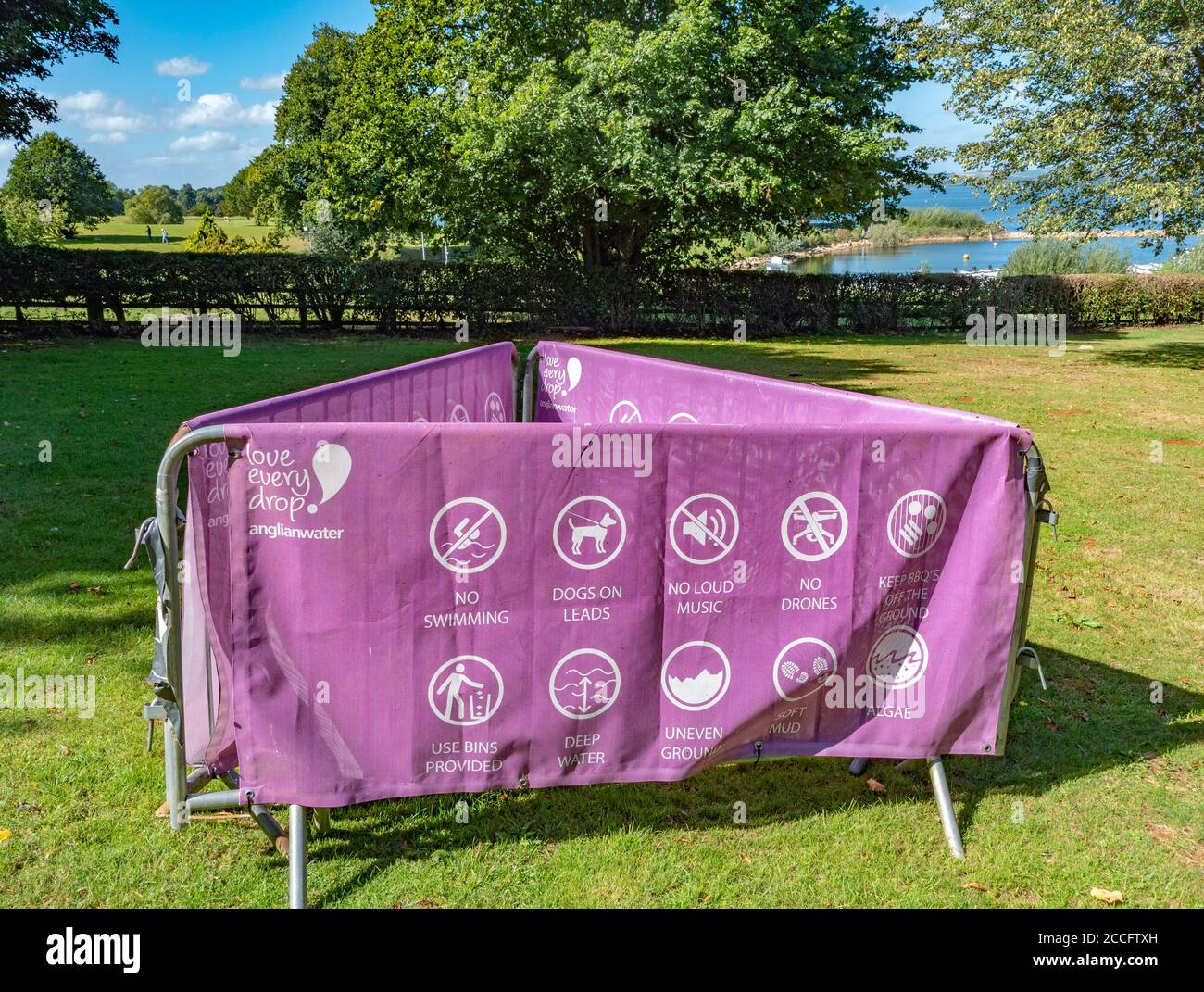 Printed canvas sign draped over metal barriers, with rules and advice to visitors at Rutland Water Park, in the summer sunshine. England, UK. Stock Photo