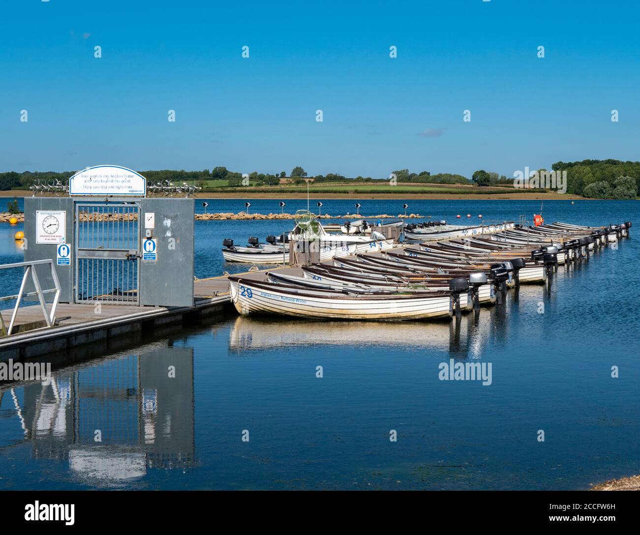 Jetty and gate leading to a line of motor boats for fishing on Rutland Water – a reservoir, artificial lake and nature reserve. Rutland, England, UK. Stock Photo