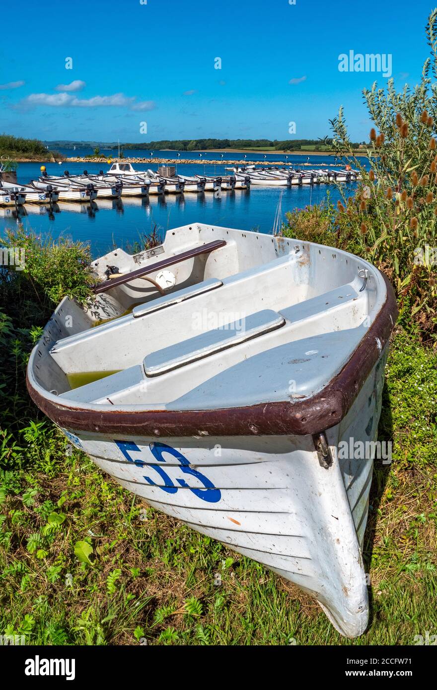 A numbered boat on land, with a line of motor boats behind on Rutland Water – a reservoir, artificial lake and nature reserve in Rutland, England, UK. Stock Photo